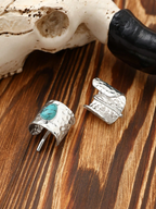 Silver ring with turquoise stone and matching cufflinks on a wooden surface