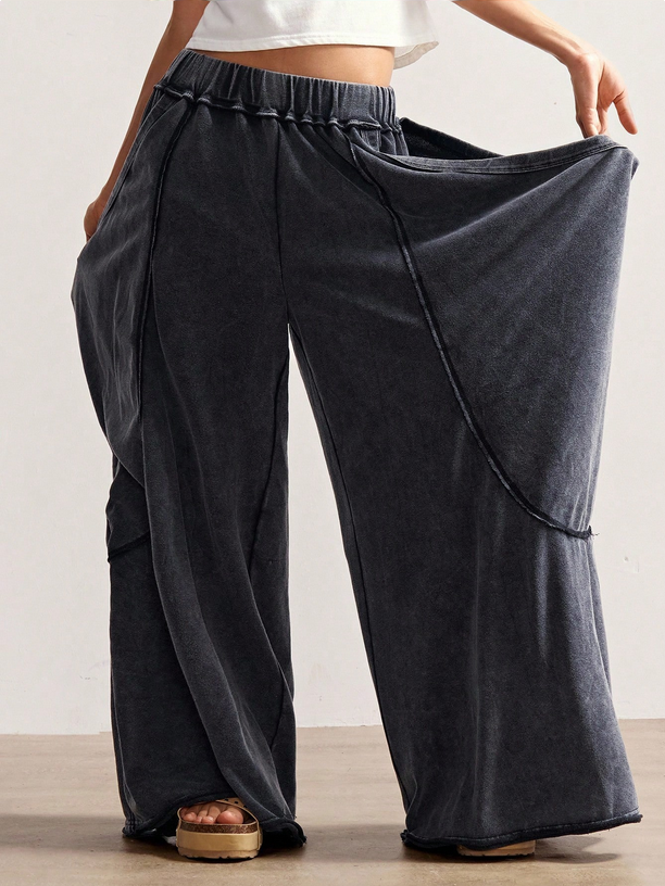 Person wearing wide-leg dark gray pants with a plain background