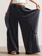 Person wearing wide-leg dark gray pants with a plain background