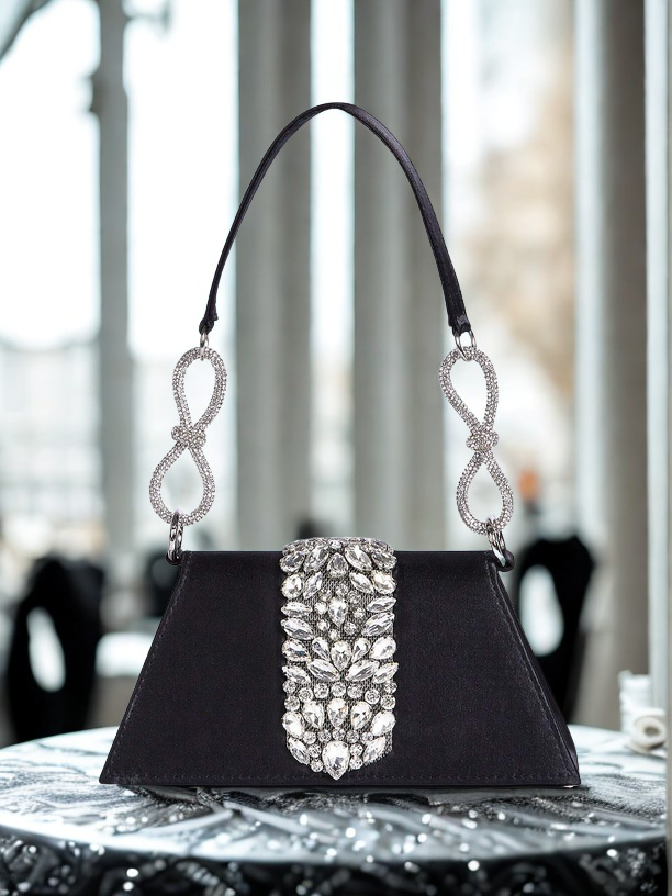 Black handbag with silver embellishments on a table
