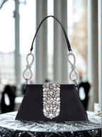Black handbag with silver embellishments on a table