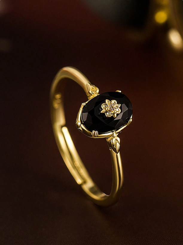 Gold ring with a black gemstone on a dark background