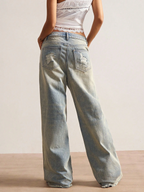 Person wearing light blue jeans with a plain background