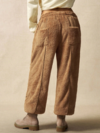Brown fuzzy pants worn by a person on a beige background