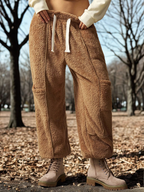 Person wearing brown fleece pants and beige boots in a park setting