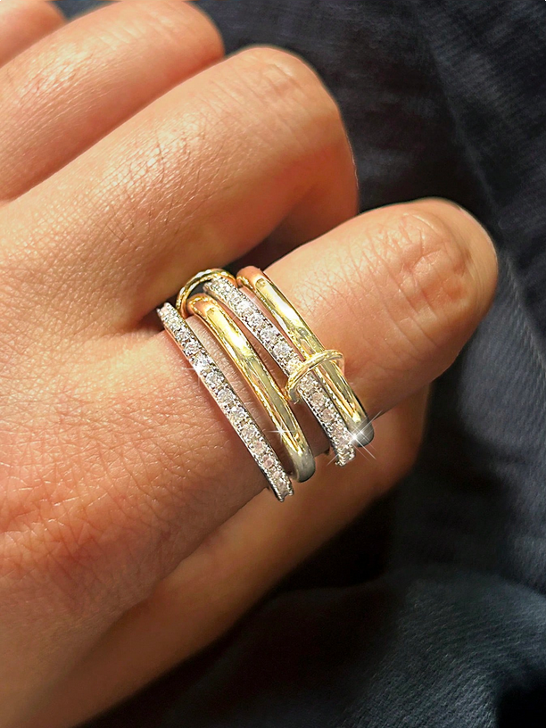 Close-up of a hand wearing two gold rings on a blurred background
