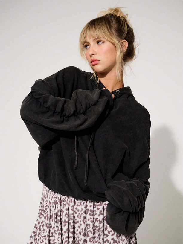 Woman wearing a black oversized sweater with a plain background