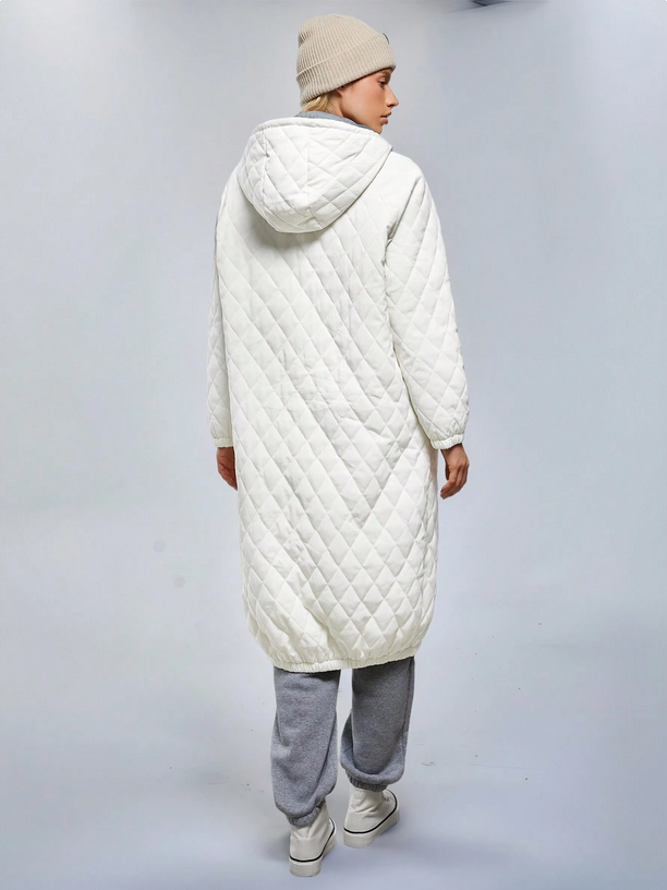 Person wearing a long white quilted coat on a plain background
