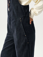 Black denim overalls worn by a person on a white background