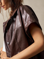 Brown leather vest worn by a person on a neutral background