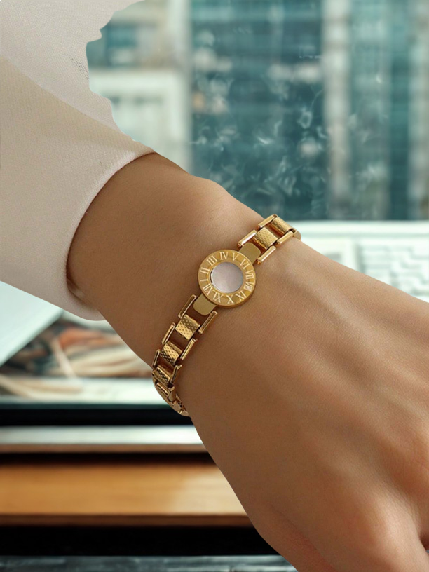 Gold bracelet on a wrist with a blurred cityscape background