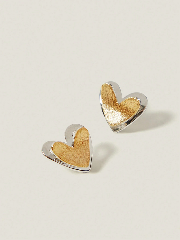 Heart-shaped earrings with gold and silver finish on a light beige background