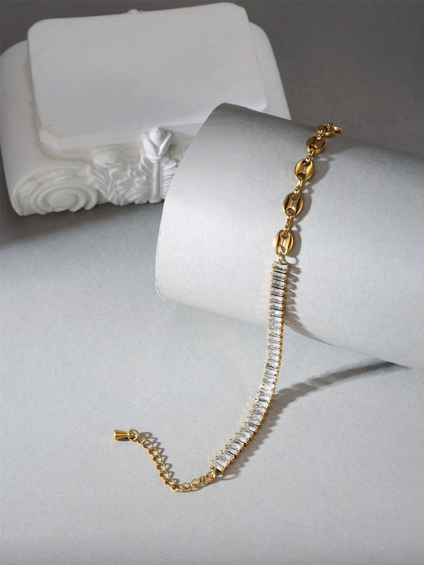 Gold bracelet with clear stones on a white mannequin hand against a gray background