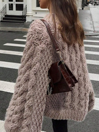 Person wearing a large knitted cardigan on a city street